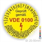 Prüfplaketten rund Farbe- Gelb, Text "Geprüft gemäß VDE 0100" in Schwarz danach ein Elektro- Pfeil in Rot, Startjahr- 26, Monatszahlen Oben und Jahreszahlen Unten in Kreisform. Über den Jahreszahlen Text "Nächster Prüftermin"