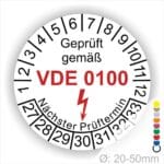 Prüfaufkleber rund, Farbe- Weiß, Text "Geprüft gemäß VDE 0100" in Schwarz danach ein Elektro- Pfeil in Rot, Startjahr- 28, Monatszahlen Oben und Jahreszahlen Unten in Kreisform. Über den Jahreszahlen Text "Nächster Prüftermin"