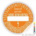 Oranges Prüfetikett mit der Aufschrift "Geprüft gemäß VDE 0701/0702", das zur Kennzeichnung von elektrischen Geräten verwendet wird. Das Etikett zeigt Platz für das Prüfdatum und den nächsten Prüftermin, Monats und Jahresring Durchmesser von 20-50 mm.
