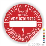 Rotes Prüfzeichen mit der Aufschrift „Geprüft gemäß VDE 0701/0702“. Das Label zeigt Platz für das Prüfdatum und den nächsten Prüftermin. Durchmesser zwischen 20-50 mm, geeignet für elektrische Geräte.