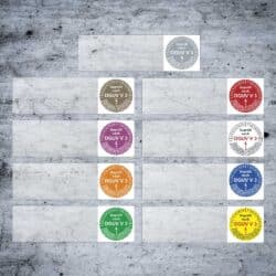 Prüfplaketten mit farbigen Texten. Diese Prüfplaketten für Kabel sind in verschiedenen Farben dargestellt: Weiß, Bronze, Rot, Lila, Orange, Grün und Gelb. Jede Plakette enthält Text, der das Jahr und den Vermerk "Geprüft nach DGUV V 3" zeigt.