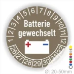 Prüfsiegel, Prüfplakette rund, Farbe- braun, Text "Batterie gewechselt" in Rot. Icon Batterie, Startjahr- 26, Monatszahlen Oben und Jahreszahlen Unten in Kreisform.
