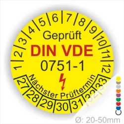 Gelbes Prüfetikett mit der Aufschrift "Geprüft DIN VDE 0751-1" und einem nächsten Prüftermin. Das Etikett zeigt eine Skala von 1 bis 12 sowie Nummern für zukünftige Prüfungen von 27 bis 33. Ø: 20-50 mm.